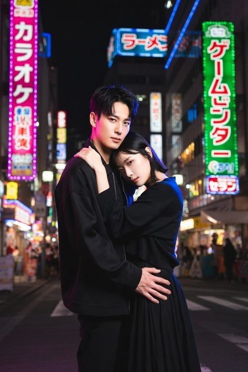 Ein Paar umarmt sich auf einer belebten Straße bei Nacht, umgeben von leuchtenden Neonreklamen in Japan.
