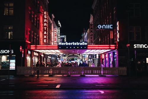 Nachtansicht der Herbertstraße mit leuchtenden Neonlichtern, Menschenmenge und bunten Lichtern an den Gebäuden.